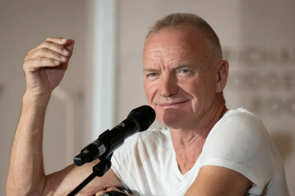 Sting, wokalista zespołu The Police, przemawia do mikrofonu, unosząc rękę w geście.