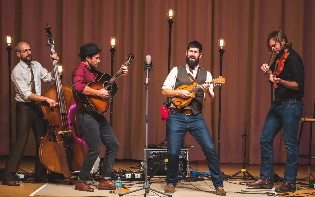 Zespół grający bluegrassową baladę na scenie: kontrabas, gitara, mandolina i skrzypce.