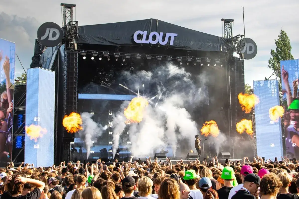 Koncert na festiwalu Clout z płomieniami i dymem na scenie. Tłum ludzi czeka na występ.