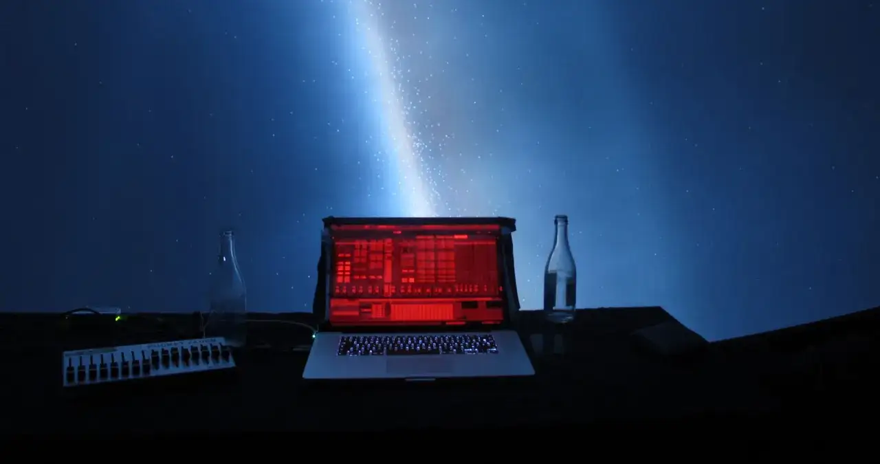Laptop z czerwonym ekranem, kontroler, butelki i rozgwieżdżone niebo. Idealne do koncertów online.