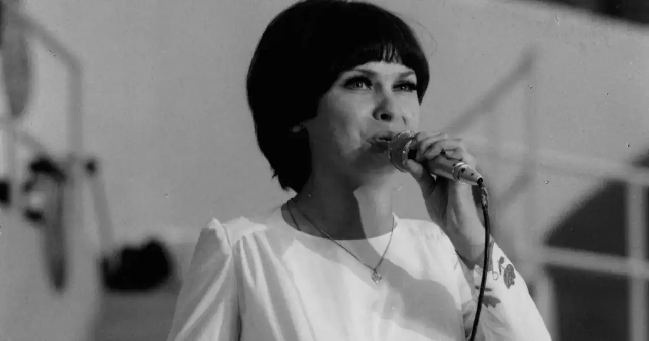 Katarzyna Sobczyk śpiewa do mikrofonu, w białej bluzce z serduszkiem na szyi. Jej życie prywatne to temat wielu rozmów.