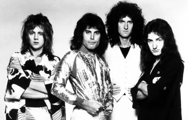 Czterech członków zespołu Queen, w tym Freddie Mercury, w stylizacjach z lat 70. Ich piosenki to ponadczasowe hity.