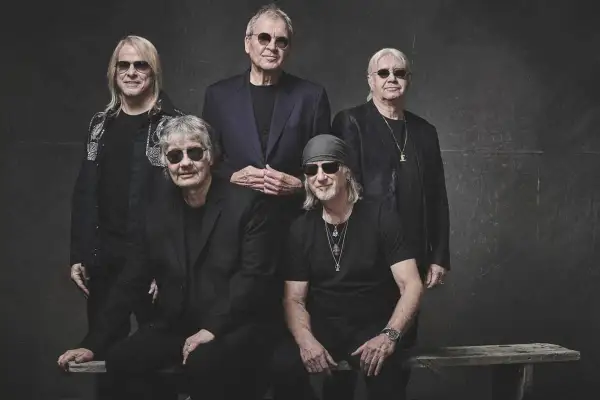 Pięciu członków Deep Purple w czarnych strojach i okularach przeciwsłonecznych pozuje do zdjęcia.