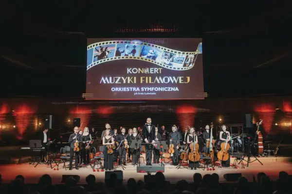 Koncert muzyki filmowej w Katowicach. Orkiestra symfoniczna na scenie pod ekranem z tytułem wydarzenia.