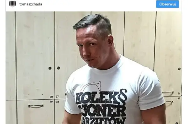 Tomasz Chada w białej koszulce z napisem "KOLEKS JONER ARZUTOW", pozuje na tle szafek.